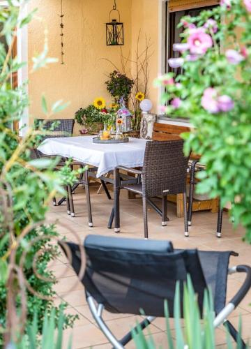 a table and chairs on a patio with flowers at Bartlhof-Ferienwohnungen-Zimmer in Burglengenfeld