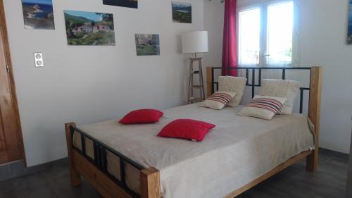 une chambre avec un lit avec des oreillers rouges et blancs dans l'établissement mini villa Marcel classée 3 étoiles, à Calenzana