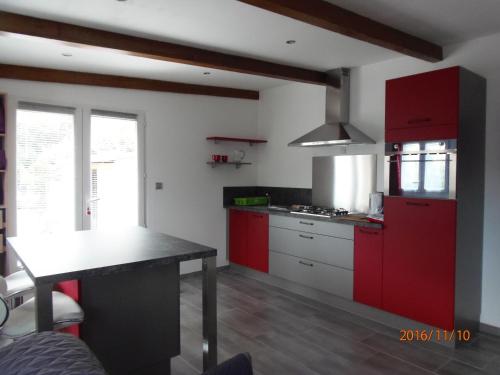 カロンザナにあるmini villa studio que du bonheurの赤いキャビネットとテーブル付きのキッチンが備わります。