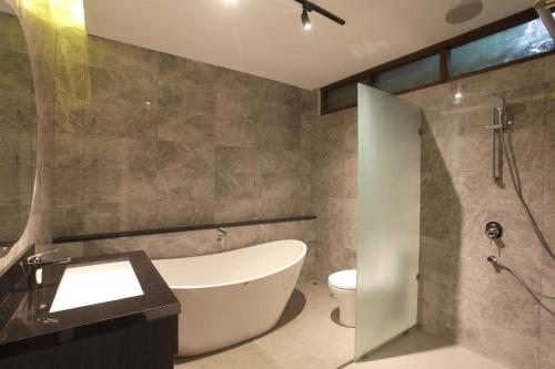 a bathroom with a tub and a toilet and a sink at Matahari Bungalow in Legian