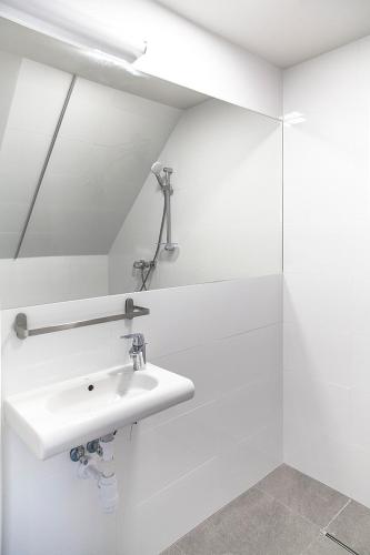 a white bathroom with a sink and a mirror at MoHo XL in Wrocław