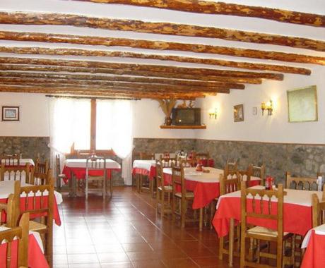 un restaurante con mesas y sillas con mantel rojo en Pensión Pallaruelo, en Saravillo