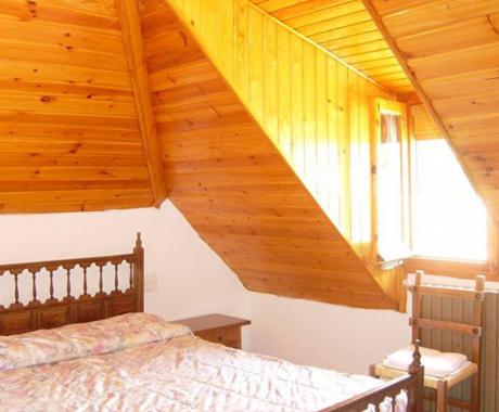 1 dormitorio con cama y techo de madera en Pensión Pallaruelo, en Saravillo