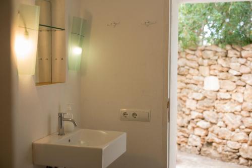 a bathroom with a sink and a stone wall at Rural Place WIFI Family Finca SAT in Sant Francesc Xavier