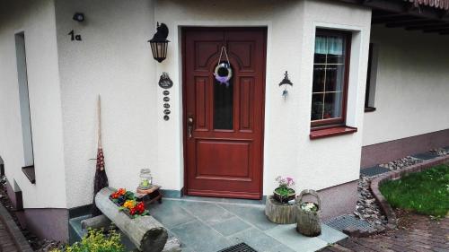 奧古斯圖斯堡的住宿－Gästezimmer Familie Müller，前方鲜花盛开的房子的红色门