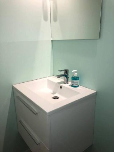 une salle de bain avec un lavabo blanc et un miroir dans l'établissement Joli 2P en Rez-de-jardin orienté SUD à 2 pas de la plage, à Cabourg