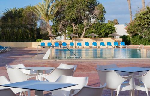 a group of tables and chairs next to a pool at Hotel Palia Don Pedro in Costa Del Silencio