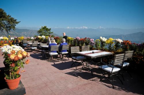 a group of people sitting at tables with flowers at Dhulikhel Mountain Resort in Dhulikhel