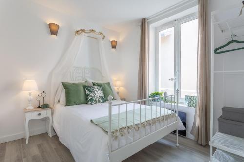 a white bedroom with a white canopy bed and a window at Le Cocon Champ&ecirc;tre in Lyon