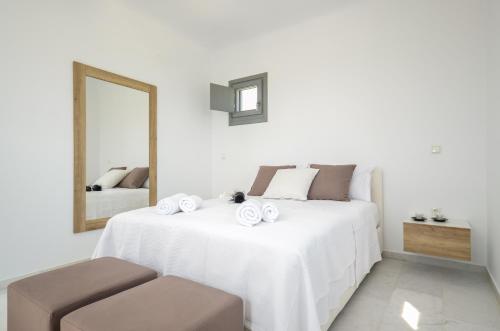 a white bedroom with a large bed with a mirror at Villa Tranquillity in Kastraki Naxou