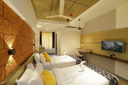 a hotel room with two beds and a flat screen tv at Bhavanam Regency Guruvayoor in Guruvāyūr