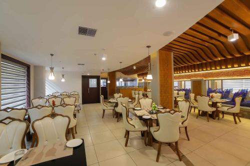 a restaurant with white chairs and tables and tablesktop at Bhavanam Regency Guruvayoor in Guruvāyūr