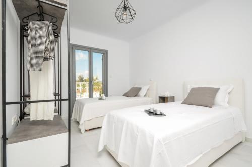 a white bedroom with two beds and a mirror at Villa Tranquillity in Kastraki Naxou