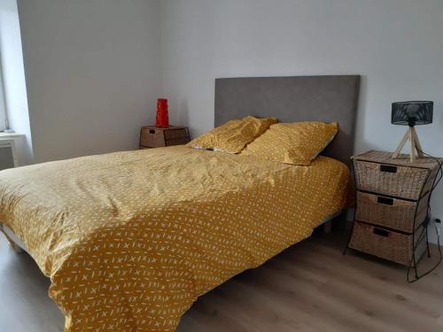 1 dormitorio con 1 cama con sábanas de oro y mesita de noche en APPARTEMENT ROUGE, en Saint-Anthème