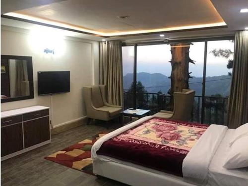 a bedroom with a bed and a balcony with a television at Snowland Hotel in Murree