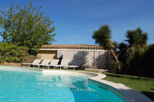 uma piscina com cadeiras e uma casa em I Lentischi em Villasimius