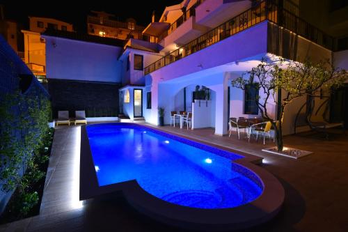 a swimming pool in front of a house at night at Klaris Guest house in Budva