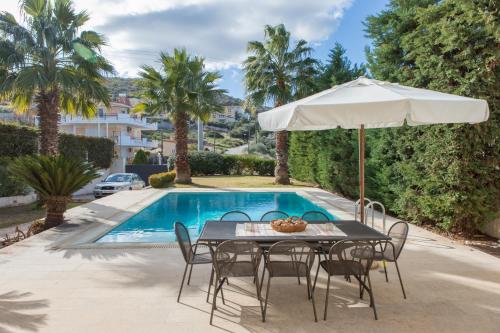 un tavolo con ombrellone accanto alla piscina di Luxury Villa Anavissos ad Anávissos
