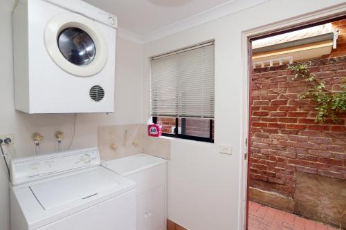 a kitchen with a washing machine and a brick wall at 230 Alice Street in Perth