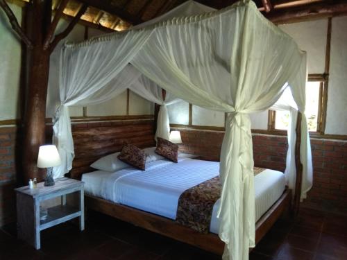 a bedroom with two beds with a canopy at Bali mountain forest cabin in Penebel