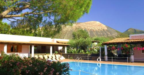 a resort with a swimming pool with a mountain in the background at Villa Saracina in Vulcano
