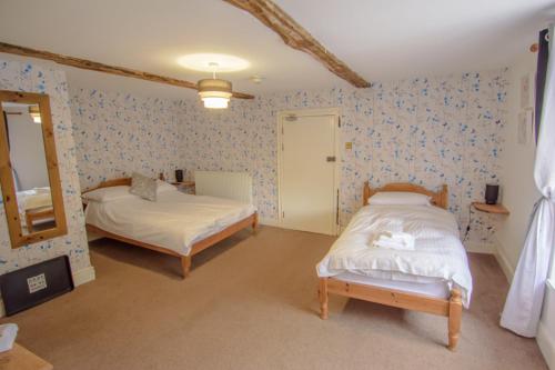 a bedroom with two beds and a mirror at The Penrhos Arms in Cemmaes