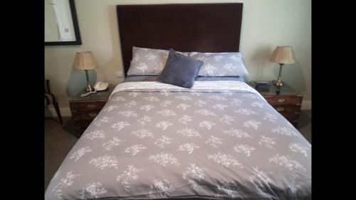 a bed with a gray comforter and two night stands at Luxury 2Bedroom Lodge in Auchterarder