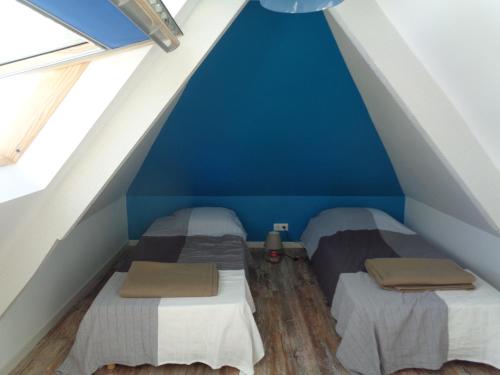 Cette chambre mansardée dispose de 2 lits, de murs bleus et de parquet. dans l'établissement Residence du Fou, à Trévou-Tréguignec