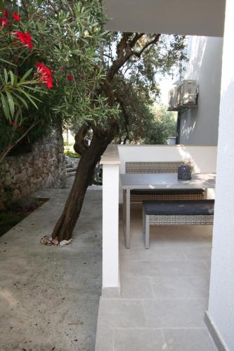 a white table and bench next to a tree at Erceg Apartmani Podgora in Podgora