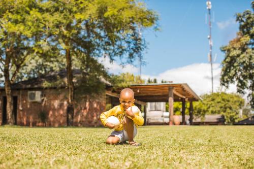 a baby sitting in the grass holding a ball at Chaminuka Lodge in Lusaka