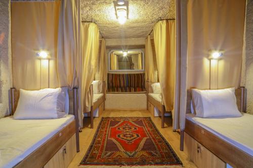 a room with two beds and a rug at Homestay Cave Hostel in Goreme