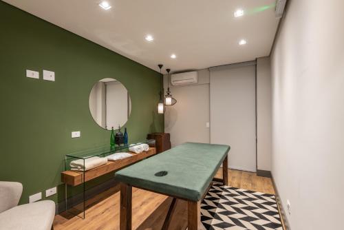 a green room with a table and a mirror at Villa Amistà Campos do Jordão in Campos do Jordão
