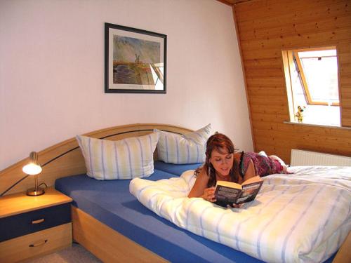 a little girl laying on a bed reading a book at Jenny´s Ferienwohnungen in Bad Salzungen