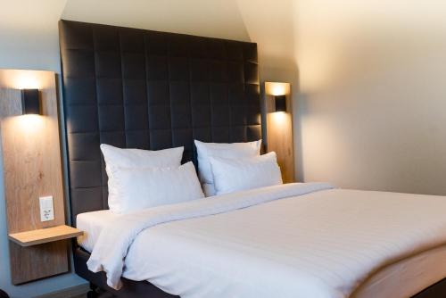 a bedroom with a large white bed with a black headboard at Hotel Circle Inn in Ramstein-Miesenbach