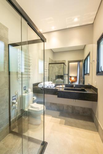 a bathroom with a glass shower and a toilet and a sink at Villa Amistà Campos do Jordão in Campos do Jordão