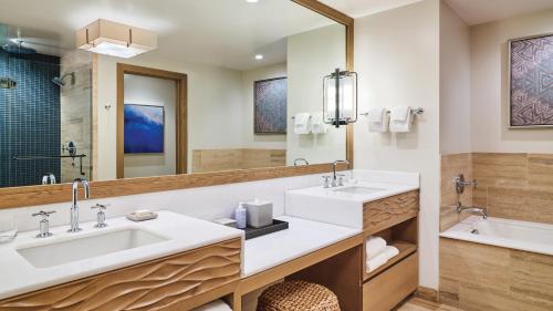 a bathroom with two sinks and a large mirror at Timbers Kauai Ocean Club & Residences in Lihue