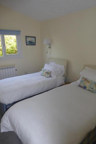 Pebble Lodges في Gurnard: سريرين يجلسون بجانب بعض في غرفة النوم
