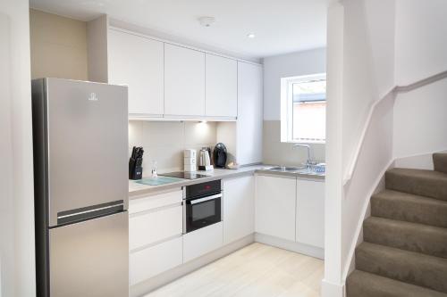 a kitchen with white cabinets and a stainless steel refrigerator at Citystay Living - Park House in Cambridge