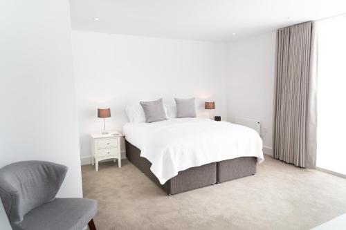 een witte slaapkamer met een bed en een stoel bij Citystay - Park House in Cambridge