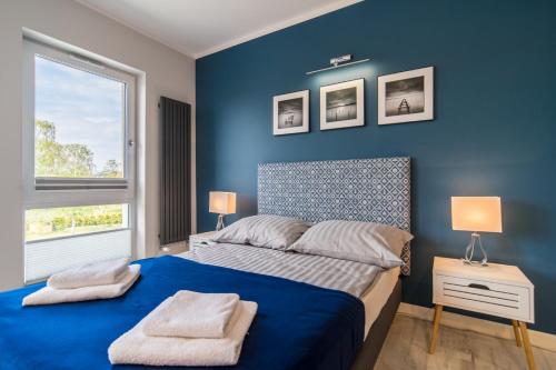 a bedroom with blue walls and a bed with two lamps at Apartamenty Pod Żaglami in Dziwnówek