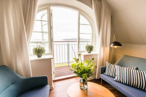 ein Wohnzimmer mit 2 blauen Stühlen, einem Tisch und einem Fenster in der Unterkunft Sixtus Sinatur Hotel & Konference in Middelfart