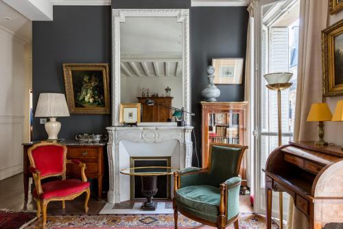- un salon avec une cheminée, des chaises et un miroir dans l'établissement Veeve - Moments From Monet, à Paris