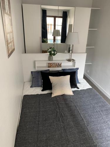 Cette chambre comprend un miroir et un lit avec des oreillers. dans l'établissement Appartement cœur de la bastille, à Paris