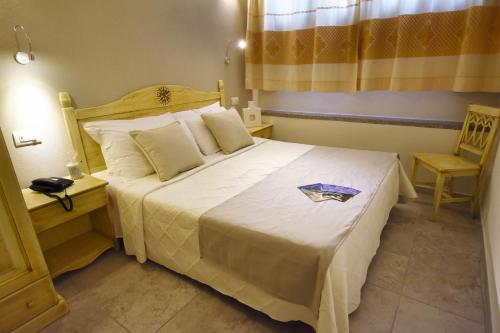 a bedroom with a large white bed and a chair at Hotel I Graniti in Villasimius