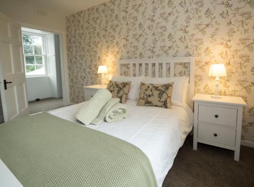 a bedroom with a white bed with two tables and two lamps at Branxholme Castle (East Wing Cottage) in Hawick