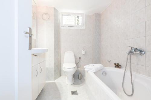 a white bathroom with a toilet and a bath tub at #FLH - Belle Reve Apartment in Thessaloniki