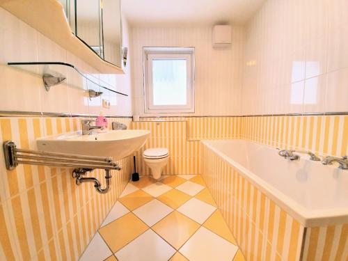 een badkamer met een wastafel, een bad en een toilet bij Achtern Diek in Warnemünde