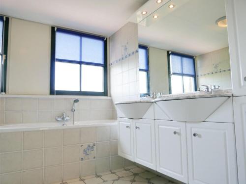 a bathroom with two sinks and a tub and a mirror at Buitenplaats Villa 5-p in Callantsoog