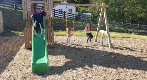 two men playing on a playground with a green slide at Slieve League House B&B in Teelin