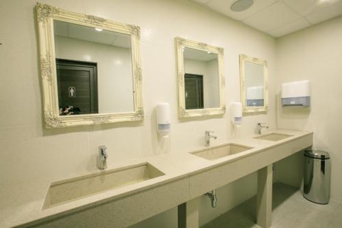 a bathroom with three sinks and two mirrors at Perun Hotel Sandanski in Sandanski